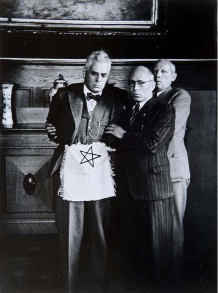 In 1941 dwingen NSB’ers de Rotterdamse burgemeester Pieter J. Oud te poseren als vrijmetselaar met een namaak-schootsvel. Collectie Vrijmetselarij Museum, Den Haag