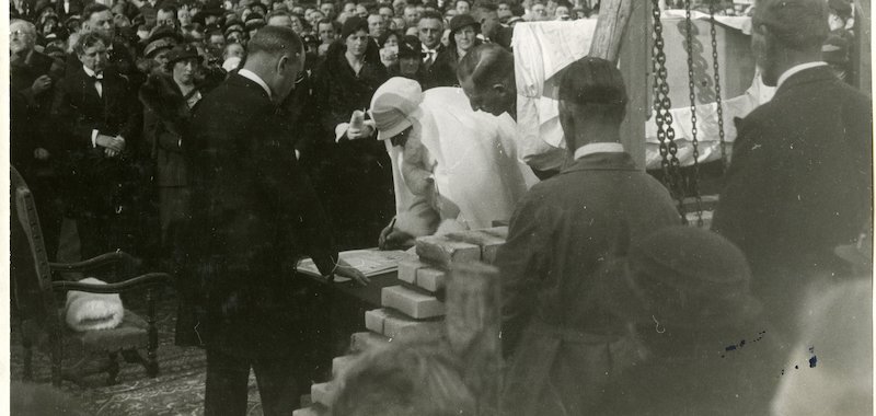 H.M. de Koningin legt de eerste steen voor de Oranjekerk, geheel links met handen over elkaar ds. D.A. v.d. Bosch (foto G Pompers)