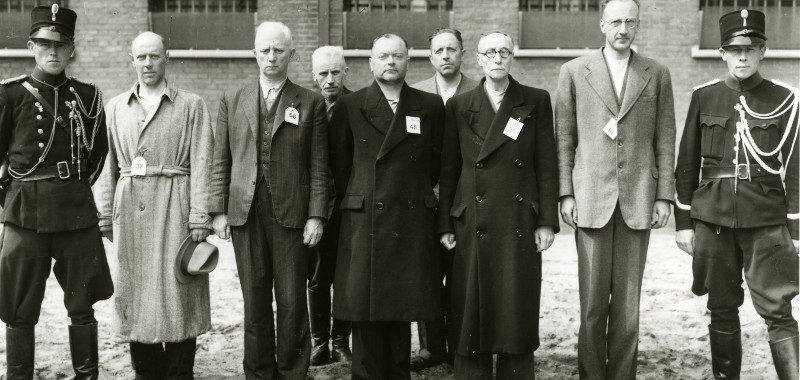 Op 11 mei 1945 zijn de kopstukken van de NSB die in het Huis van Bewaring in de Casuariestraat in Den Haag waren opgesloten gefotografeerd. In het midden Anton Mussert, met naast zich aan zijn linkerzijde de voormalige NSB-burgemeesters van Den Haag Harmen Westra en de lange Henri van Maasdijk.